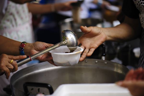 person receiving bowl with ladled food
