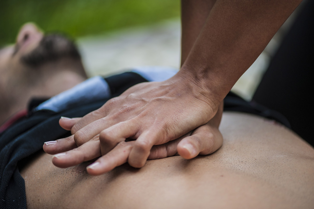person performing hands only CPR on man