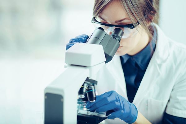 scientist peering into microscope