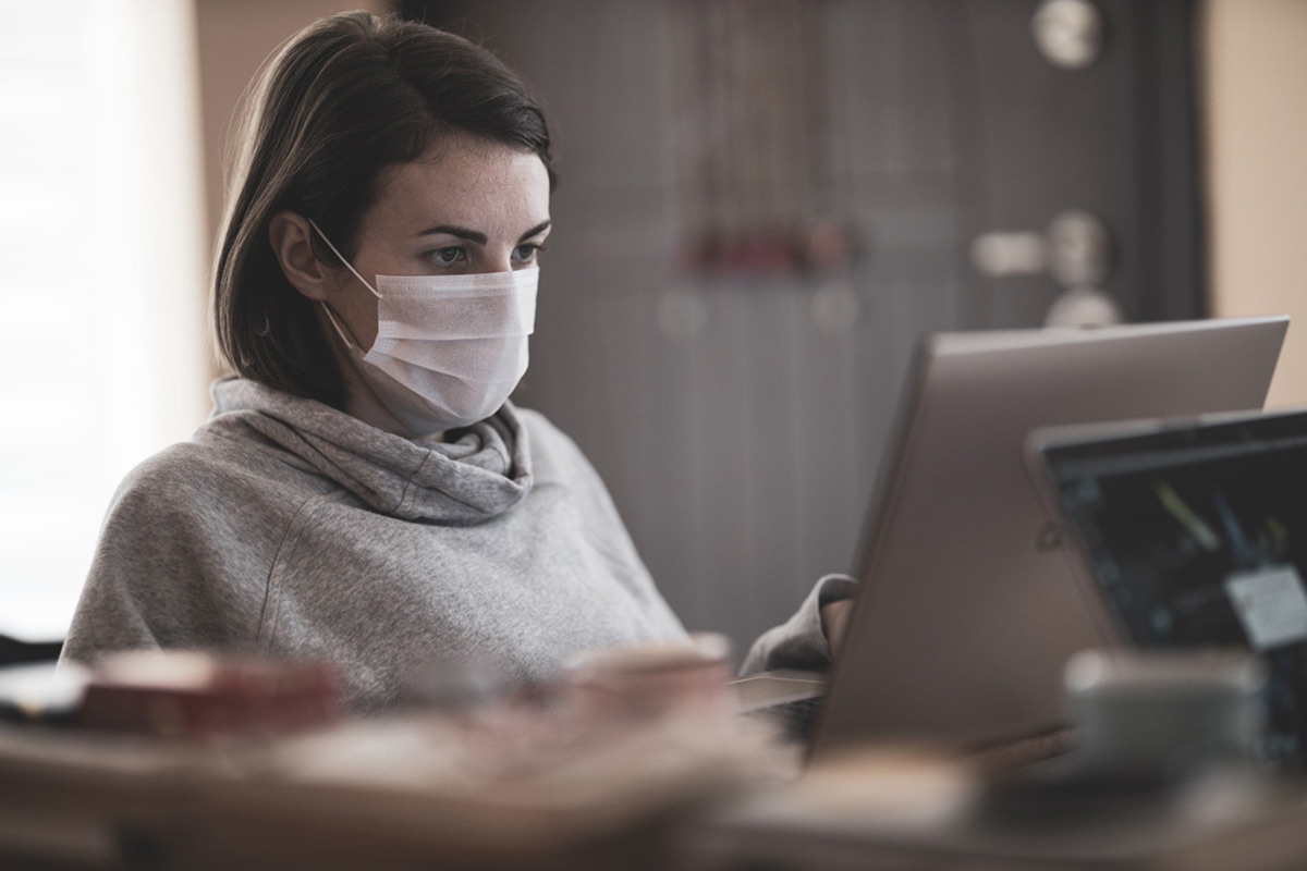 woman sitting in front of computer wearing a mask