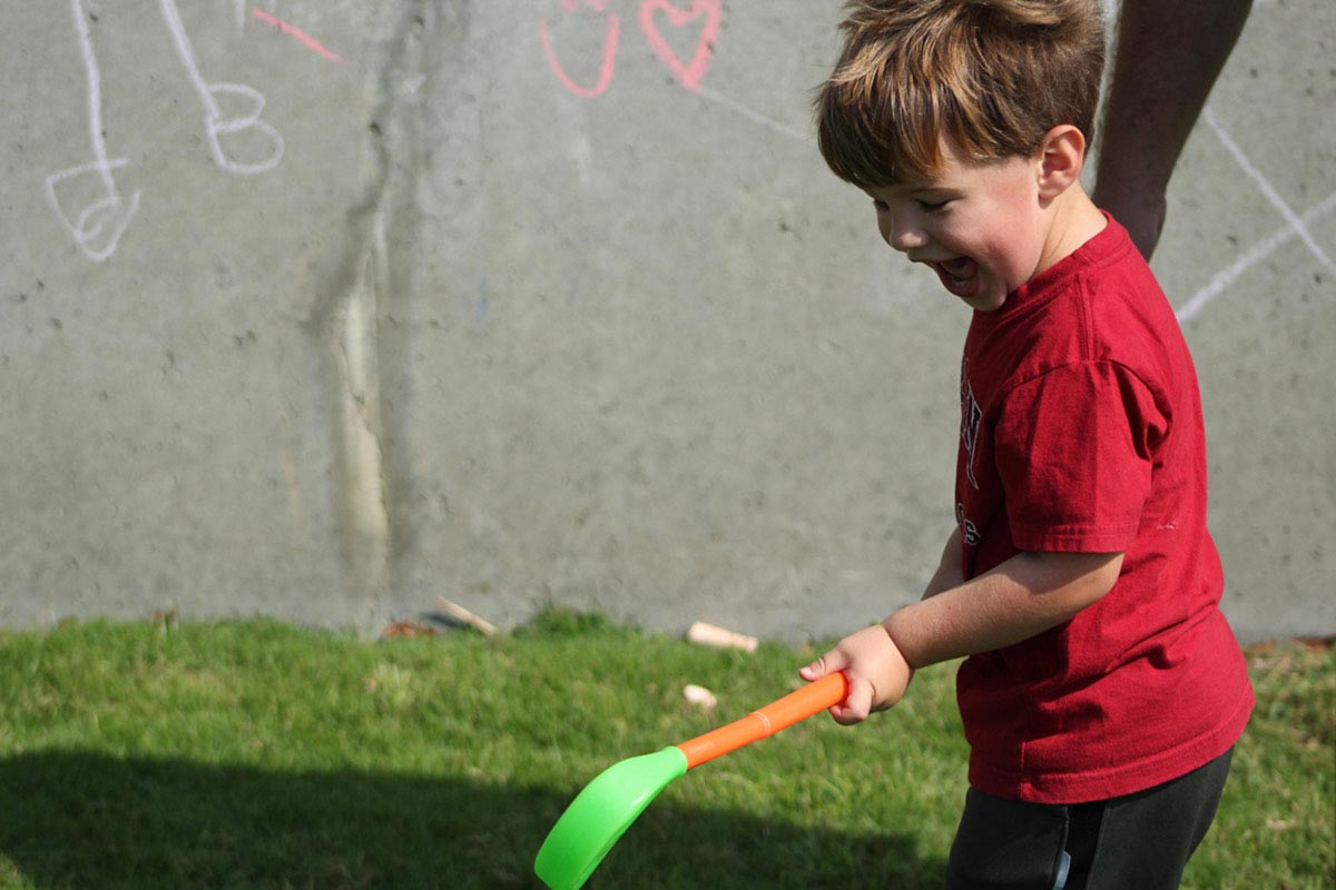 boy playing outdoors with toy hockey stick