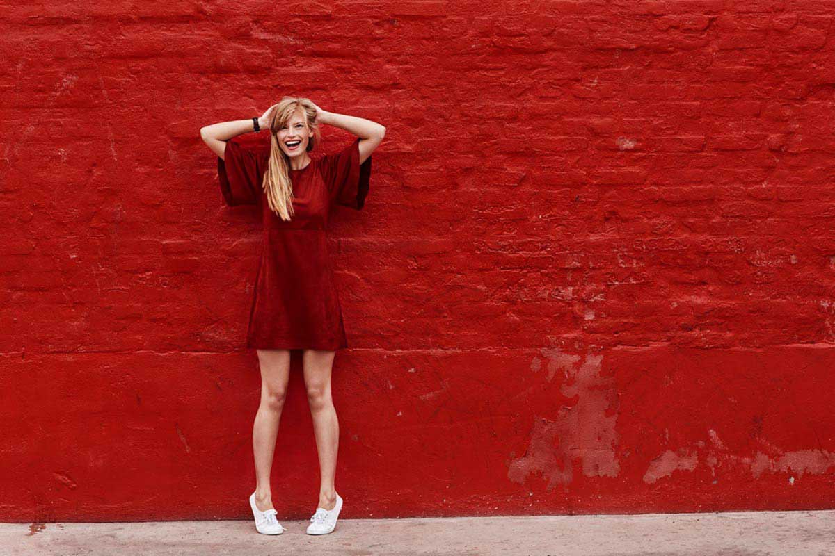 woman in red dress in front of red brick wall