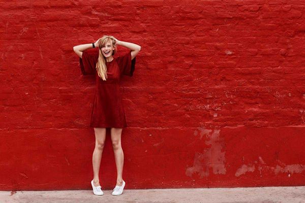 woman in red dress in front of red brick wall