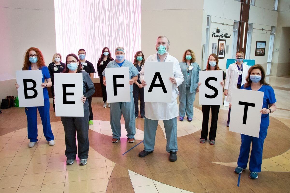 healthcare workers in masks holding up letters spelling BE FAST