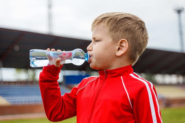 young boy in red jacket drinking a bottle of water