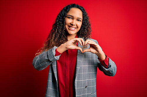 woman holding heart hands with red background