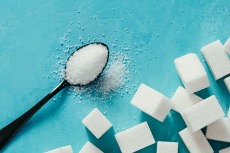 image of sugar cubes and a spoonful of sugar on a teal background