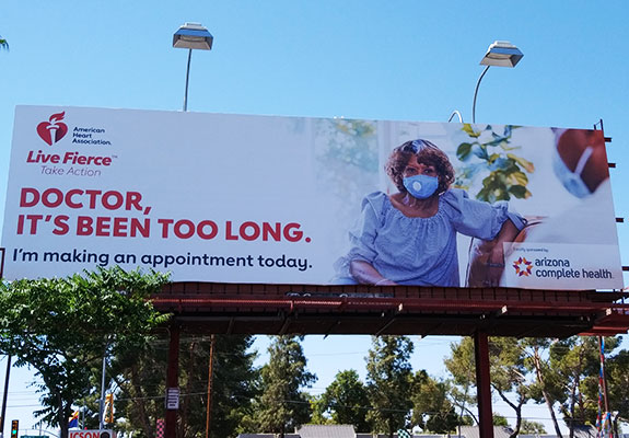 billboard in Tucson Arizona with the American Heart Association logo that reads "Doctor, It's Been Too Long. I'm making an appointment today. Locally sponsored by Arizona Complete Health."