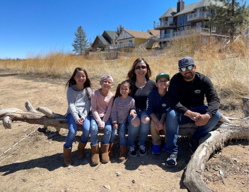 Olivia Story with her parents and siblings posing for a picture sitting on a wood stump