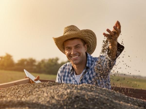 smiling man at sunset holding up grain