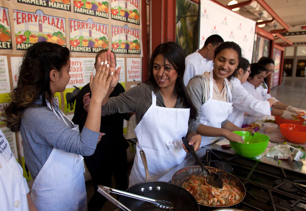 Kids high five as they cook. Gallileo High School junior Maria Salvador, left, and senior Dina Moncada-Choukri high five each other at the conclusion of their Iron Chef-style cookoff against Mt. Diablo High School students at the Bay Bridge Teens Cook with Heart Challenge at the Ferry Building in San Francisco, March 17, 2014. (D. Ross Cameron/Bay Area News Group)