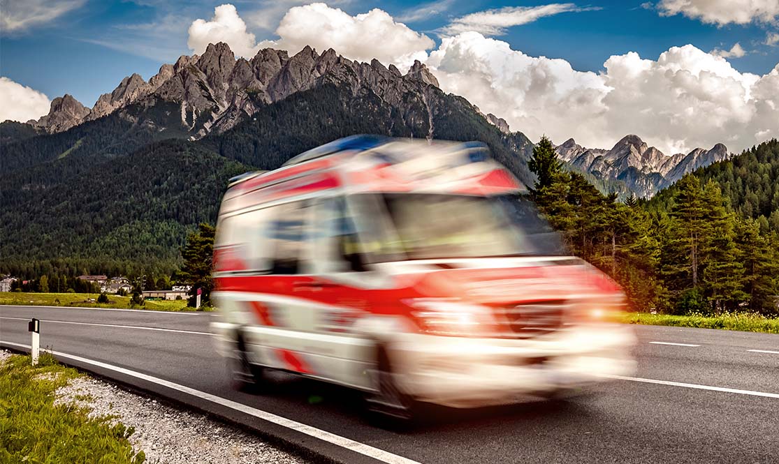 ambulance driving down two lane highway in the mountains