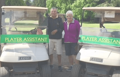 Saving Strokes volunteers standing near golf carts that read "player assistant"