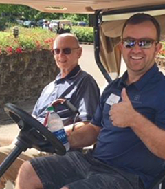 Two smiling men in a golf cart