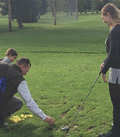 man and child helping woman golf