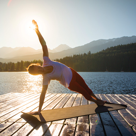 Woman doing yoga on a dock near a lake