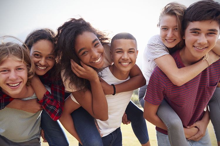 Group of teenagers smilling, some on piggyback