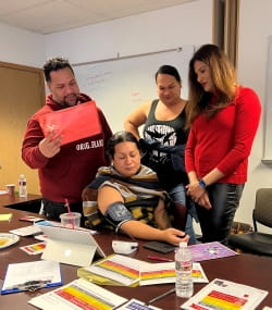 group of three people looking on as one woman takes her blood pressure