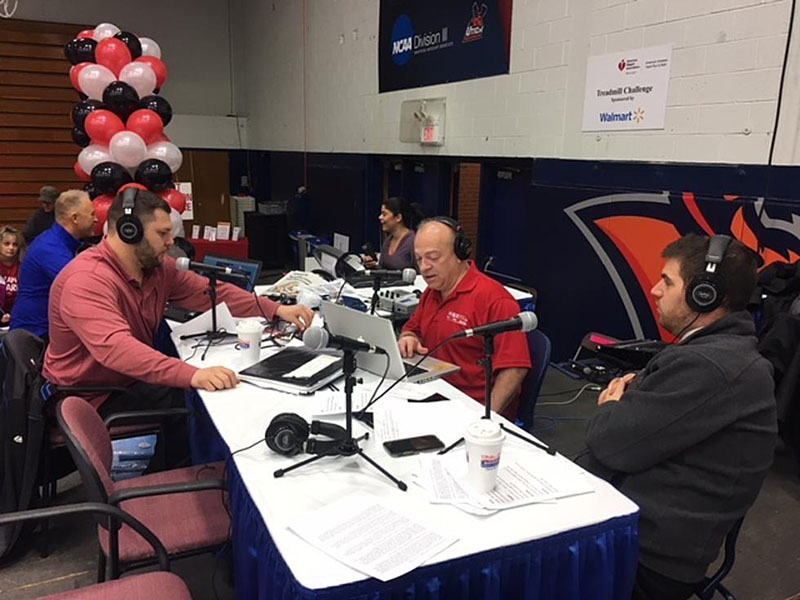 From left: Jeff Monaski, Bill Keeler and Andrew Derminio of WIBX during a Heart Radiothon before the pandemic, on stage in the gym at Utica College for America’s Greatest Heart Run & Walk. To their left are two Treadmill Challengers. 