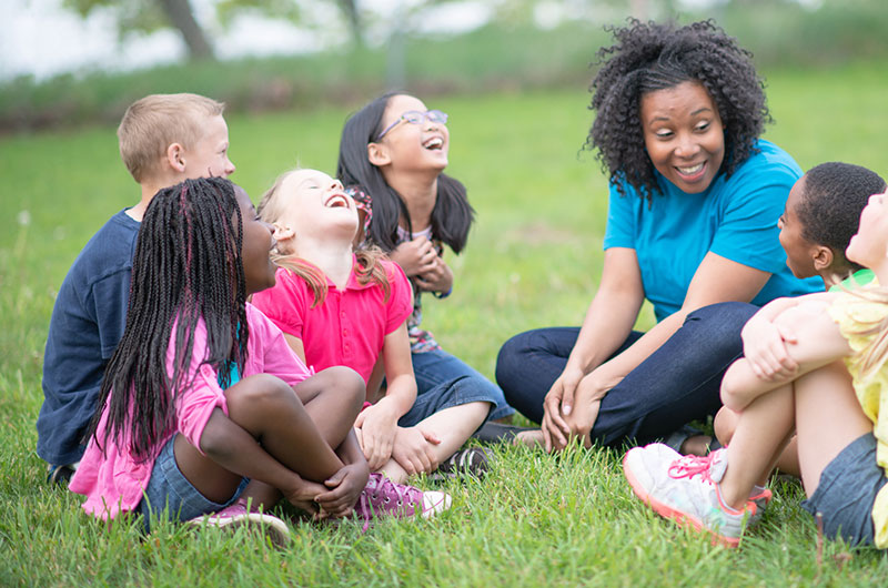 teacher with young children sitting in a circle outdoors