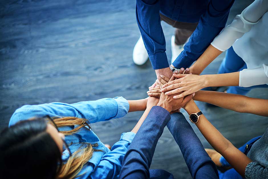 people in a circle with hands stacked on top of one anothers