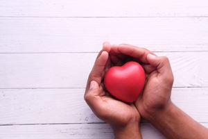 close up of hands holding a cartoon heart-shaped stress ball