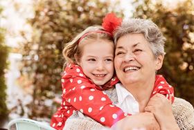 Smiling grandmother and granddaughter sharing a hug outdoors