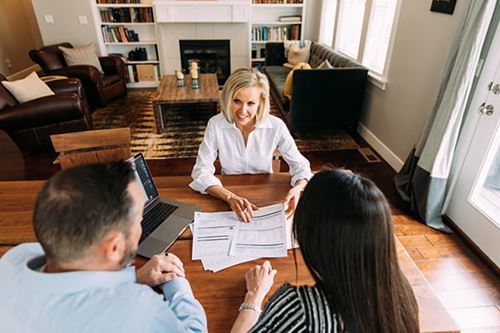 A couple consults with a financial advisor and looks over documents in their living room