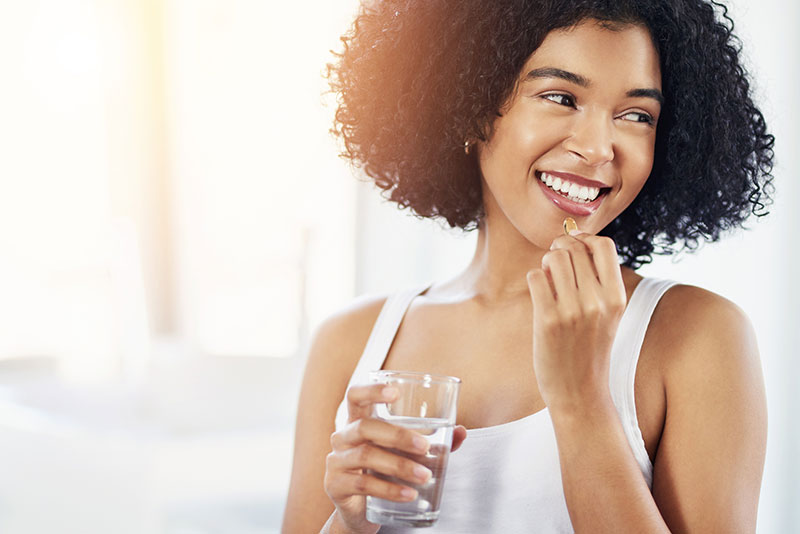happy woman taking pill with water