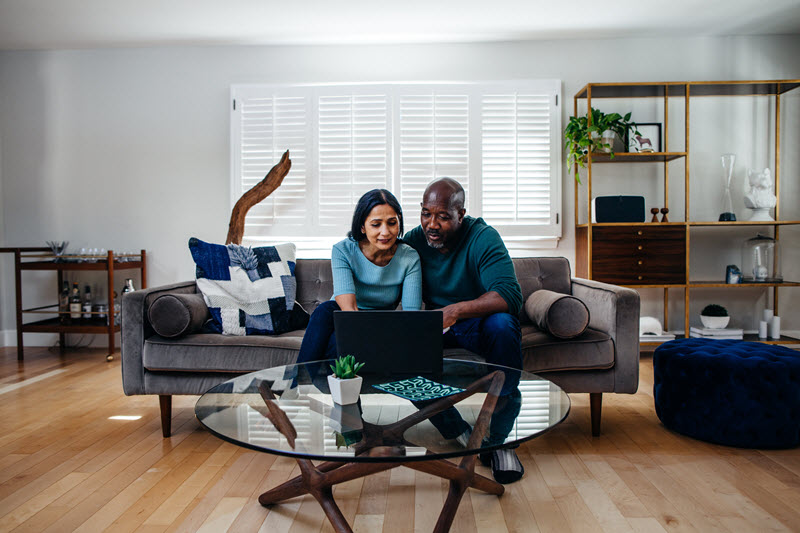 couple sitting on couch using laptop