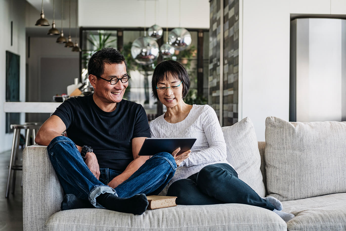 older Asian couple using tablet on the couch