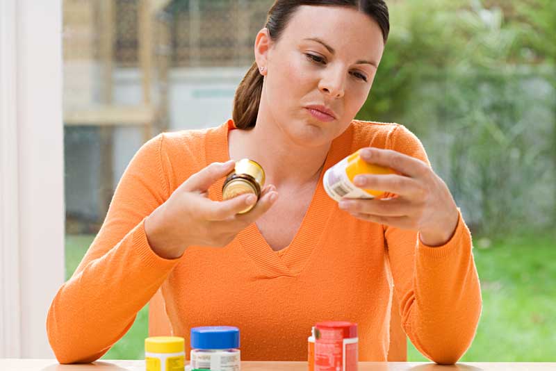 woman reading labels on pill bottles