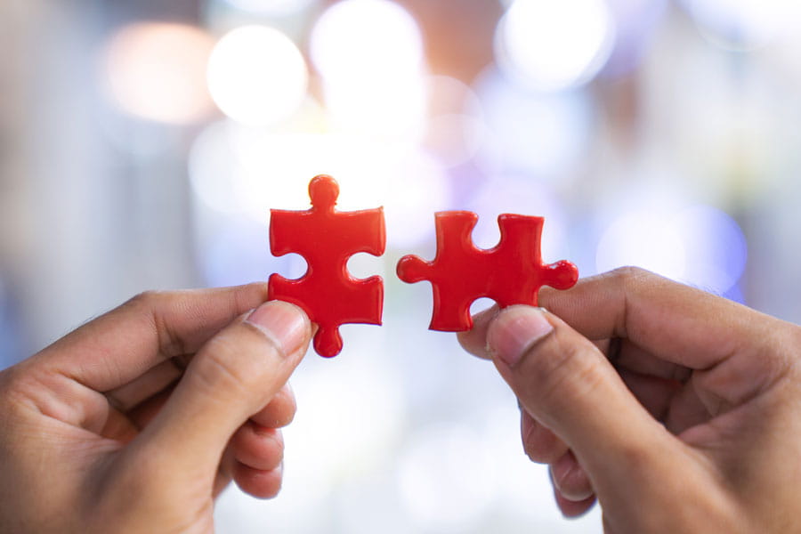 Hands holding two pieces of a jigsaw puzzle