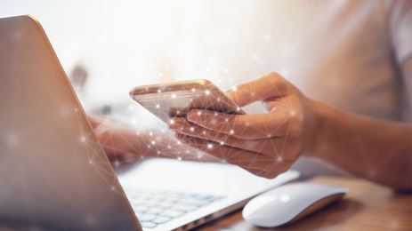 Woman emailing using mobile phone or laptop