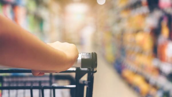 close up of arm pushing cart in isle of grocery store