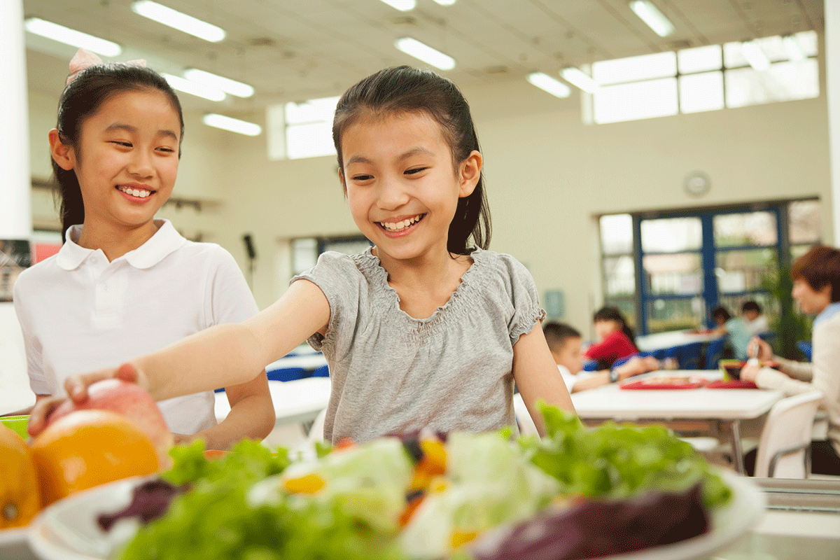 happy elementary students choose food in school lunch line
