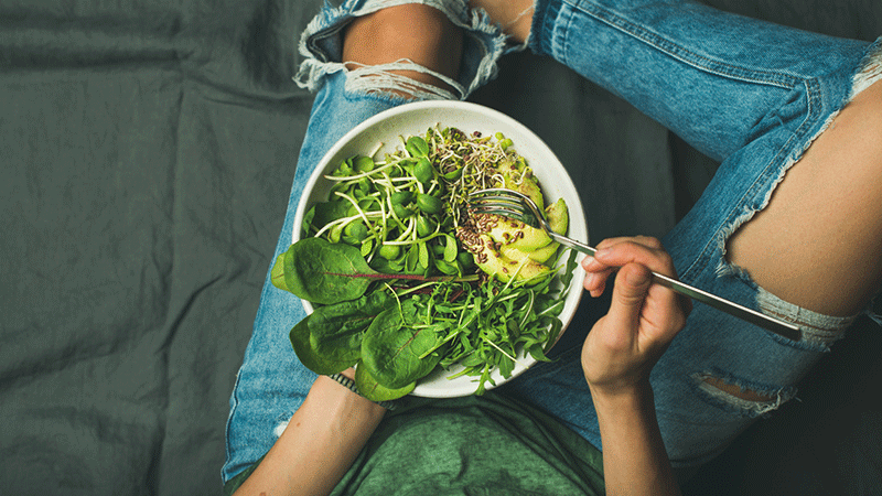 woman in ripped jeans eating salad