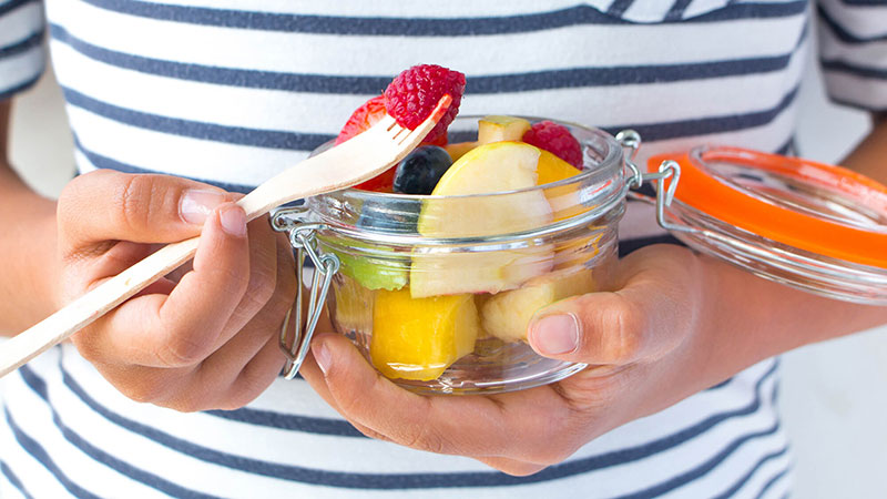 Person with a jar of assorted fruit 