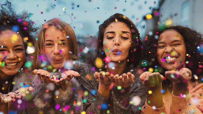 happy diverse girlfriends celebrate with confetti