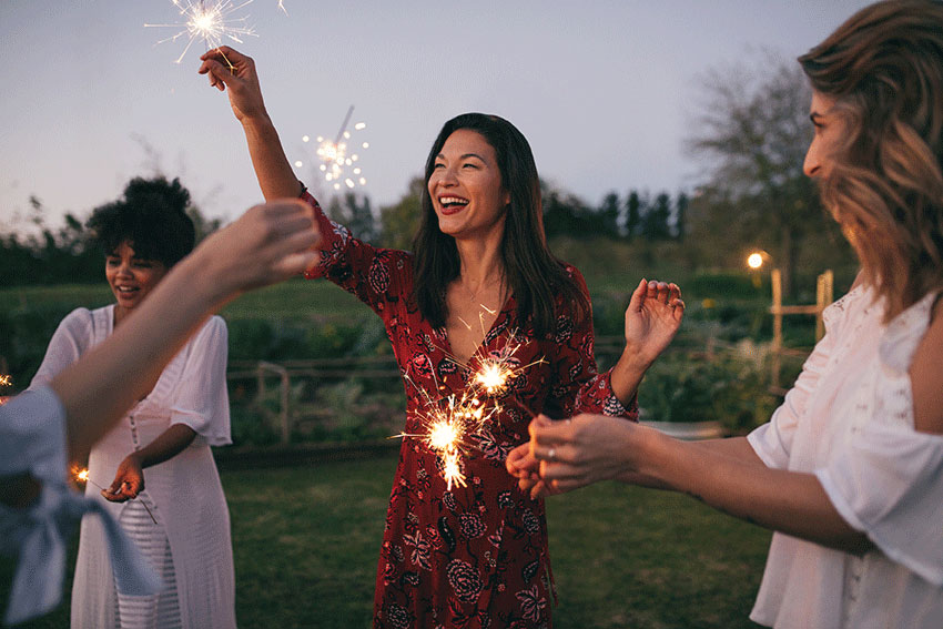 happy friends playing with sparklers outdoors