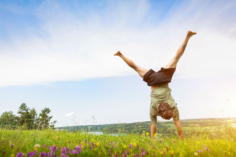 Young man doing a handstand in a grassy field