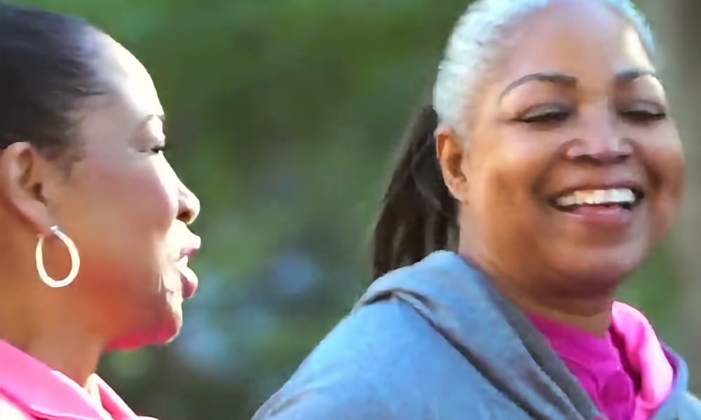 two women smiling while walking