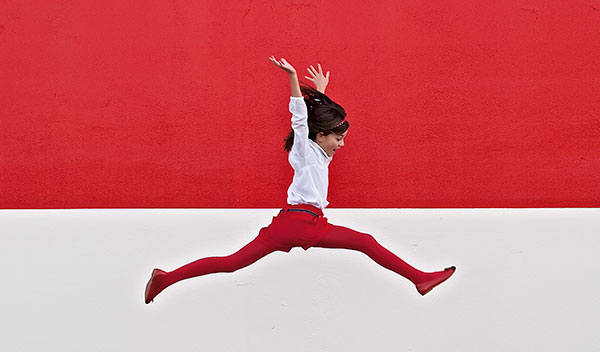 Girl jumping in front of red background