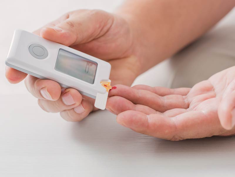 Hands pricking finger to test for insulin.