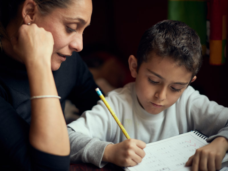Hispanic mother helping son with homework.
