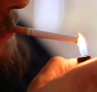 Bearded man lighting cigarette.