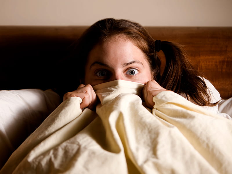 Close up of a young scared and frightened woman, covering herself