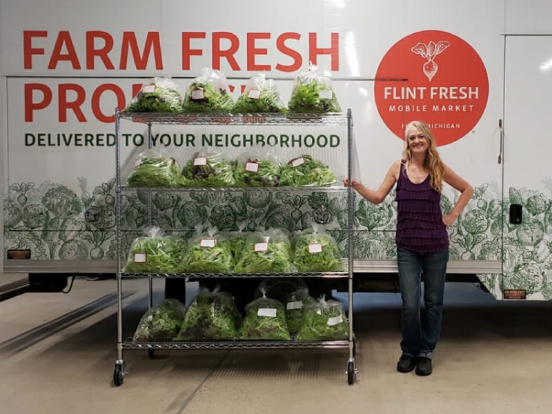 A Flint Fresh employee shows off some of the produce delivered by the organization’s mobile market truck.