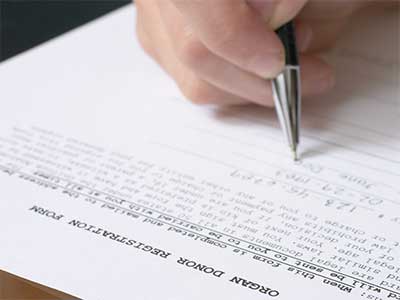 close up photo of person's hand filling out organ donor form
