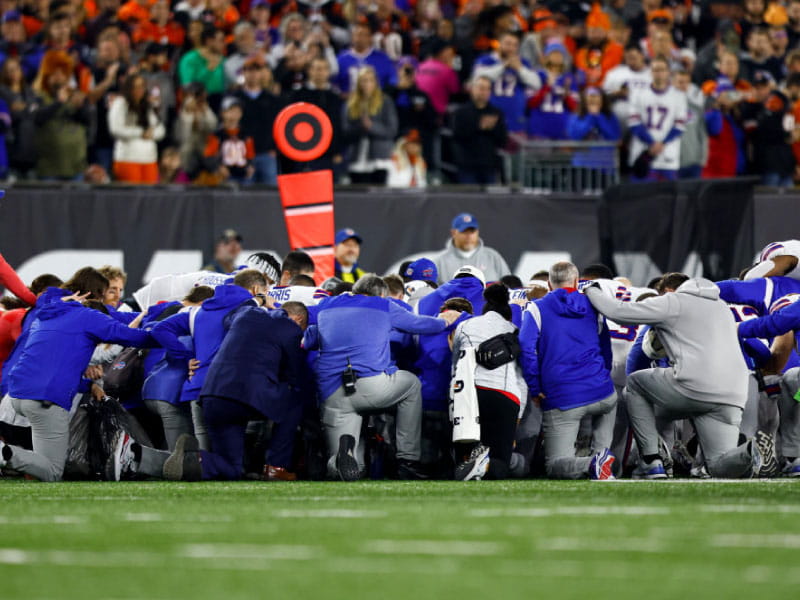 Buffalo Bills players and staff kneel after Damar Hamlin collapsed during an NFL football game against the Cincinnati Bengals on Jan. 2, 2023 in Cincinnati. (Kevin Sabitus/Getty Images)